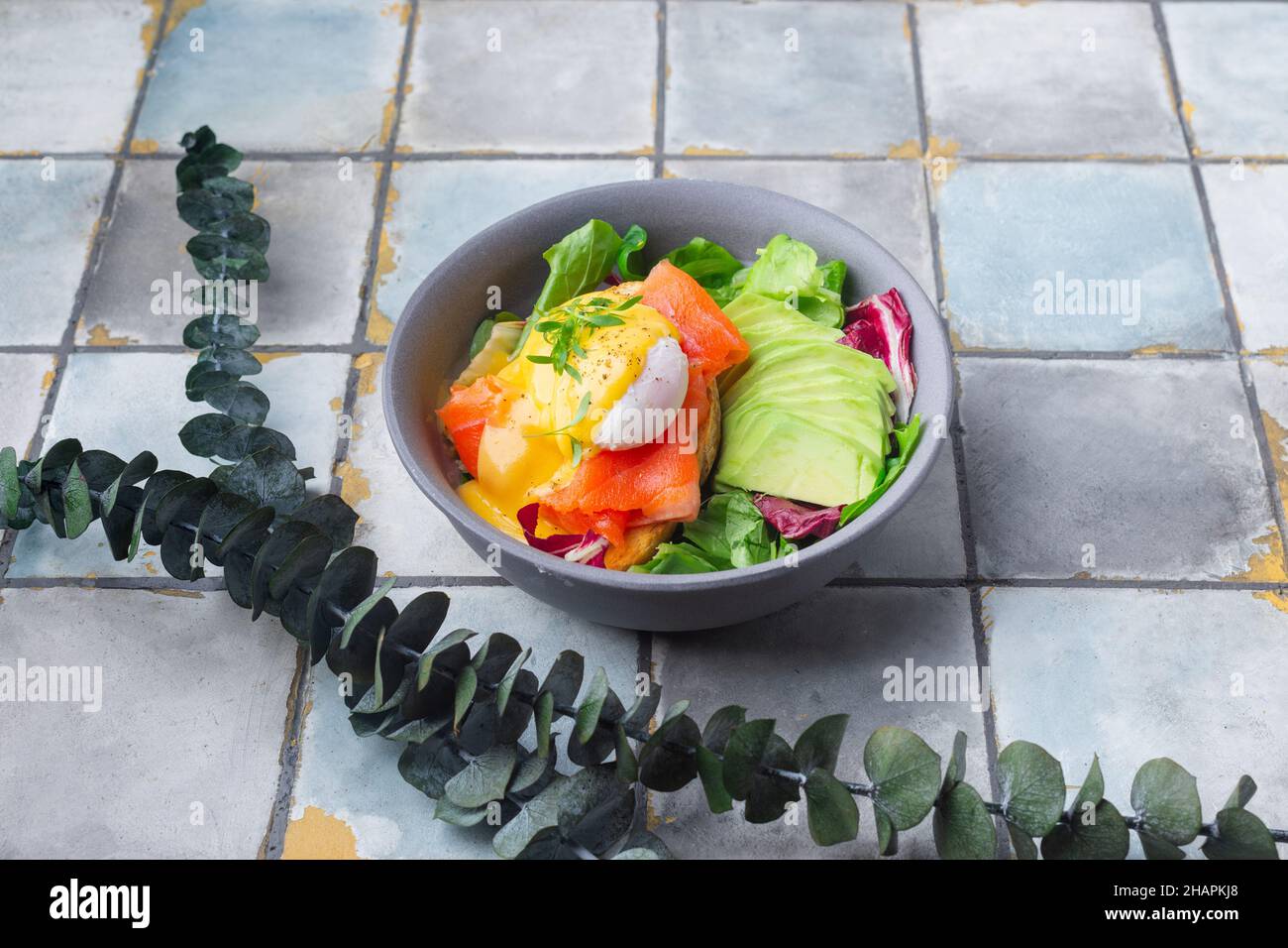 Delicious breakfast, brunch - poached egg, salmon, avocado, arugula salad on a tile background Stock Photo