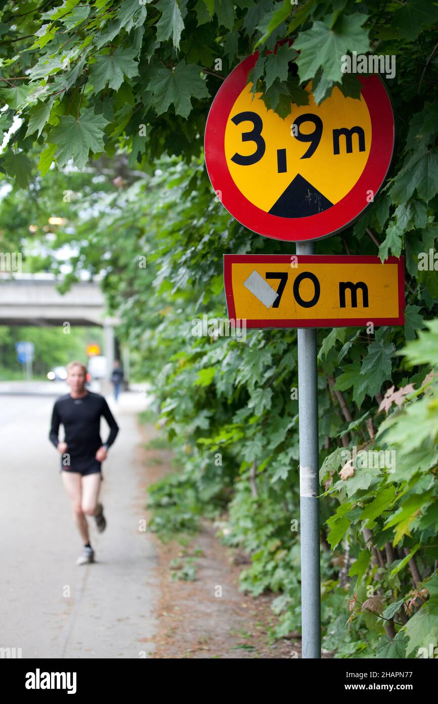 Stockholm, Sweden - June 7, 2010: A bridgde height sign in the foreground and a blurred runner running towards the camera. Indicates a 3,9 meter high Stock Photo