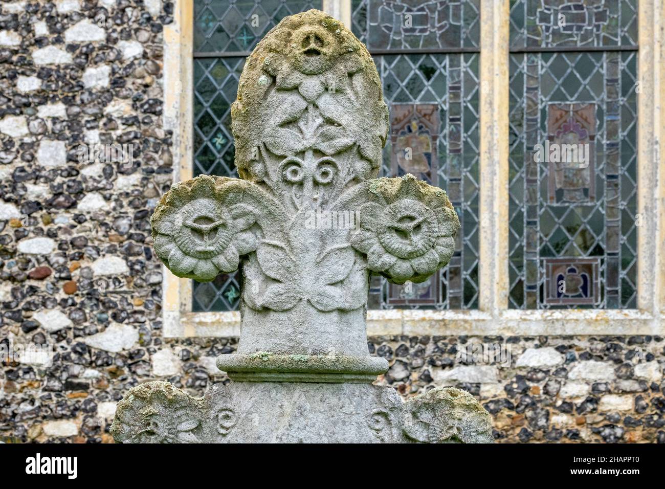 Exterior window detail with carved headstone in the foreground at the Church of St Mary of the Assumption, Ufford, Suffolk Stock Photo