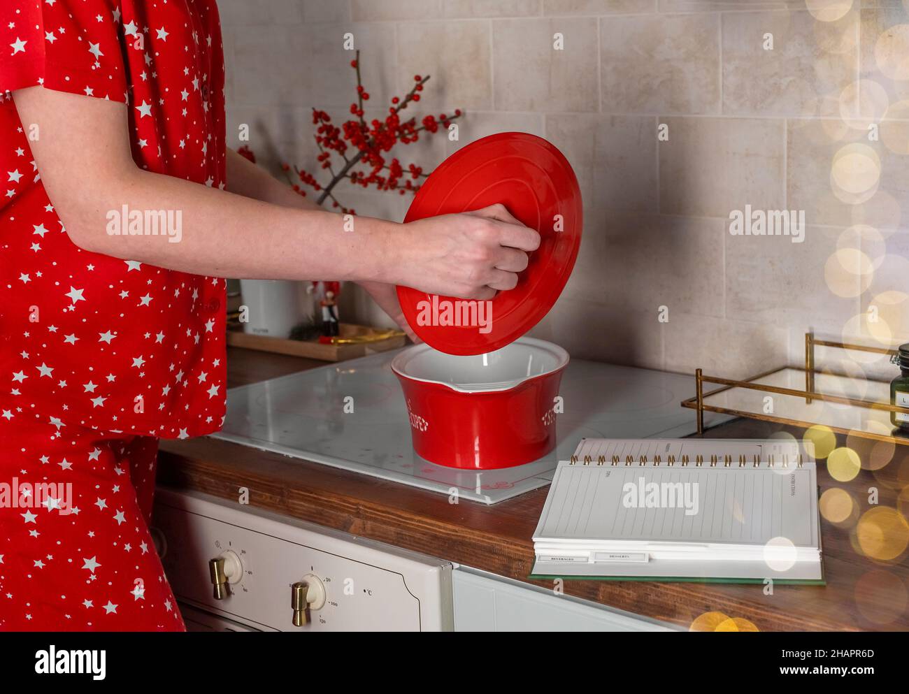 Cooking dinner in red pot with recipe book at home kitchen. Stock Photo
