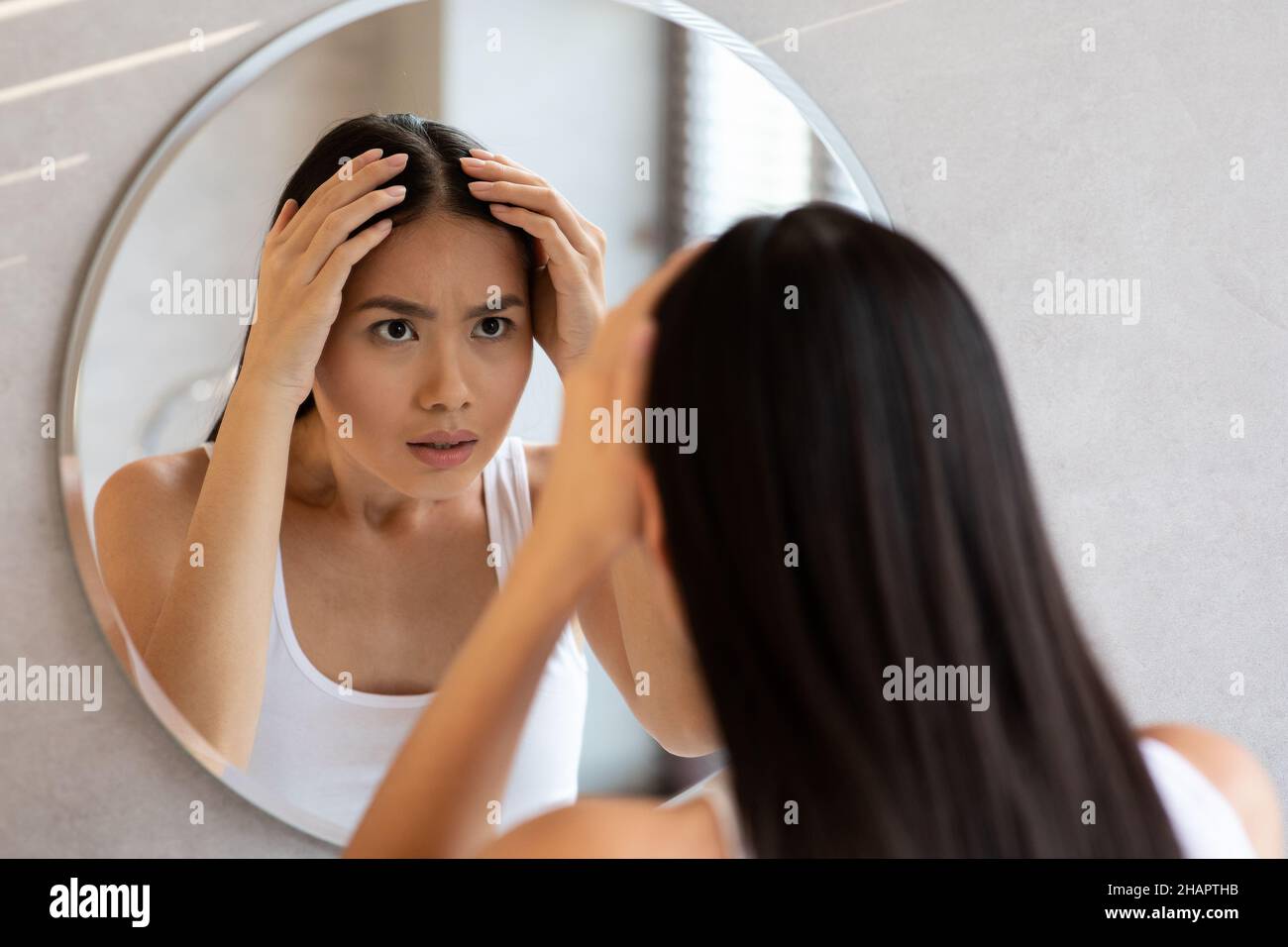 Worried long-haired chinese woman checking her hair Stock Photo