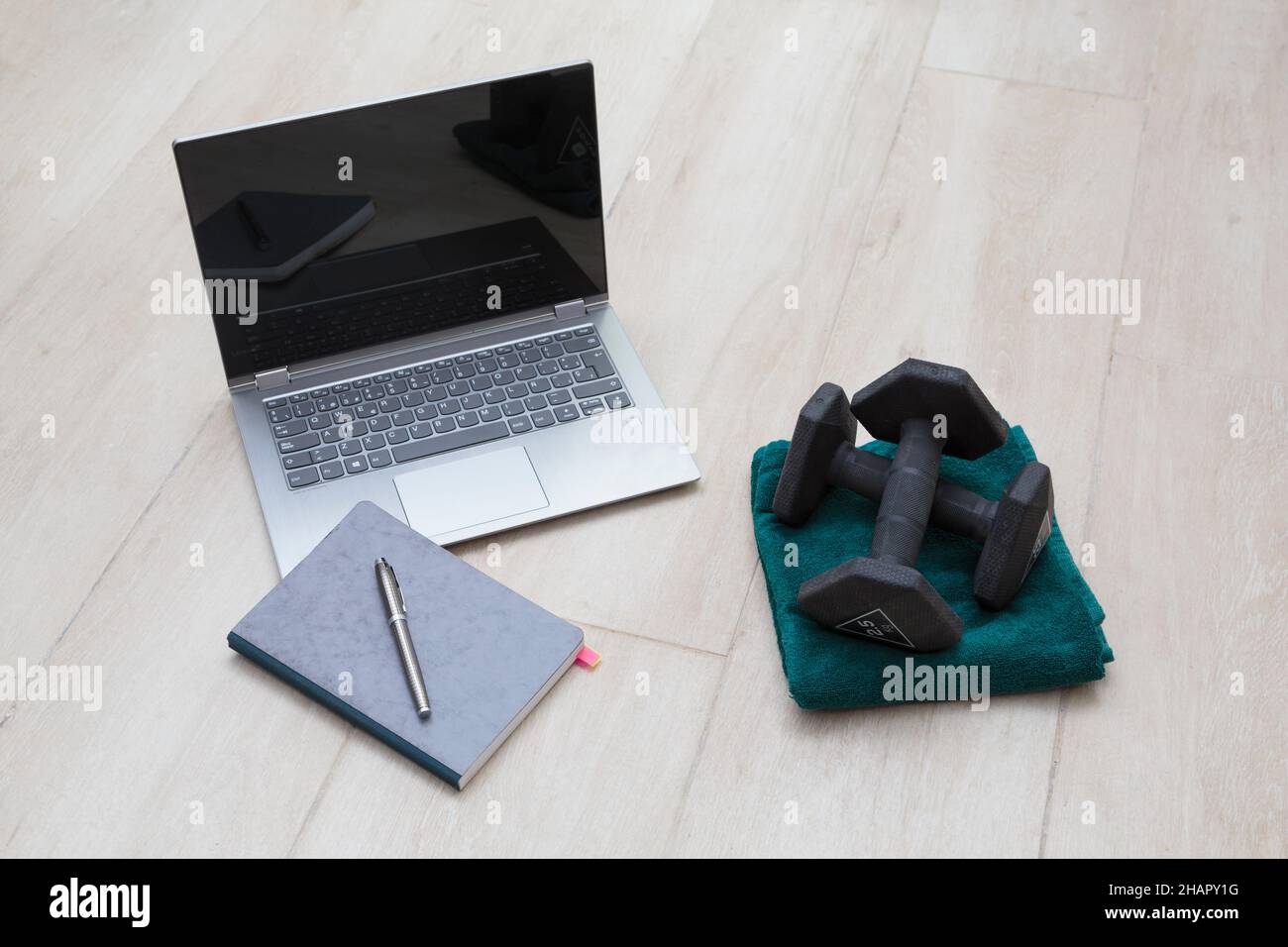 A laptop, a notebook and a pair of dumbbells Stock Photo
