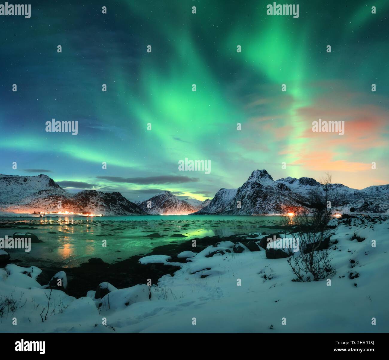 Aurora borealis over the sea coast, snowy mountains and city Stock Photo