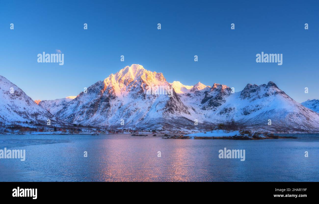 Beautiful snow covered mountains and blue sky reflected in water Stock Photo