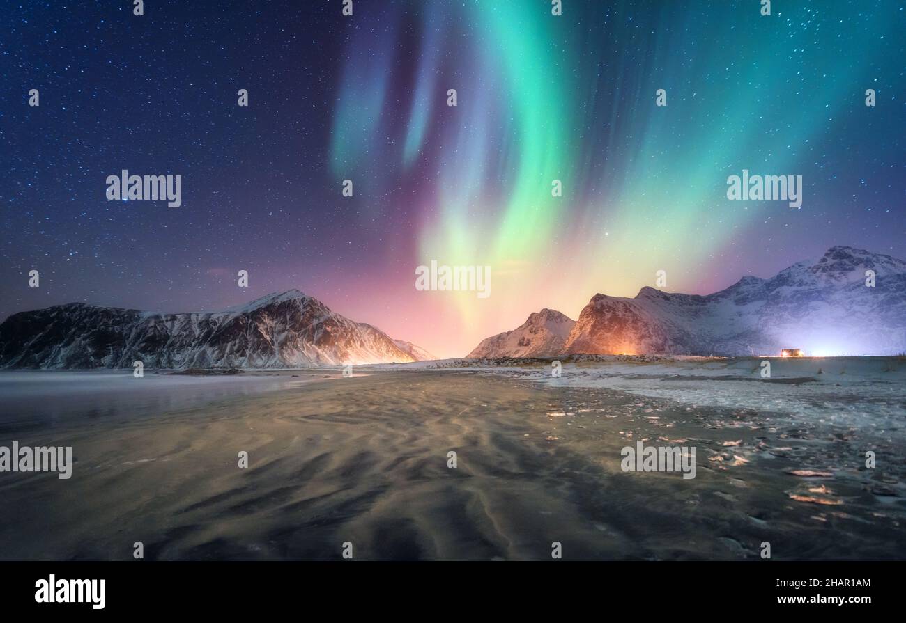 Aurora borealis above the snowy mountain and sandy beach Stock Photo
