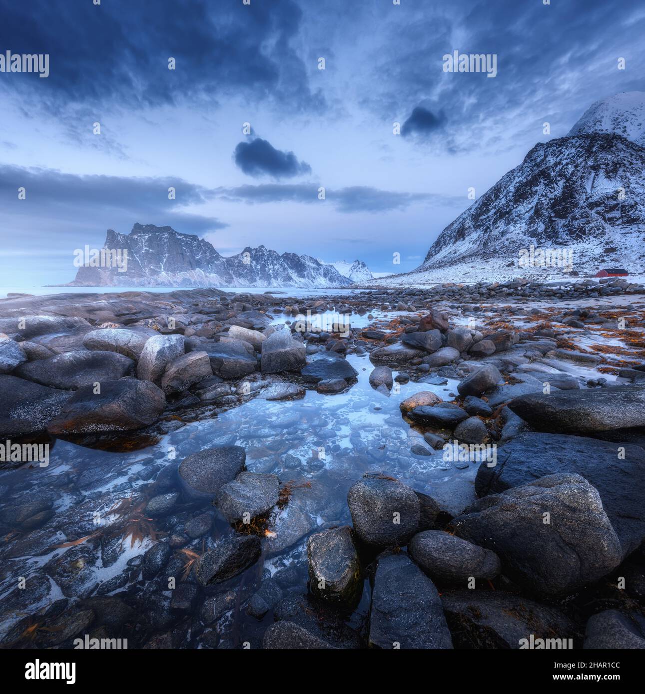 Seashore with stones and blurred water, against snowy mountains Stock Photo