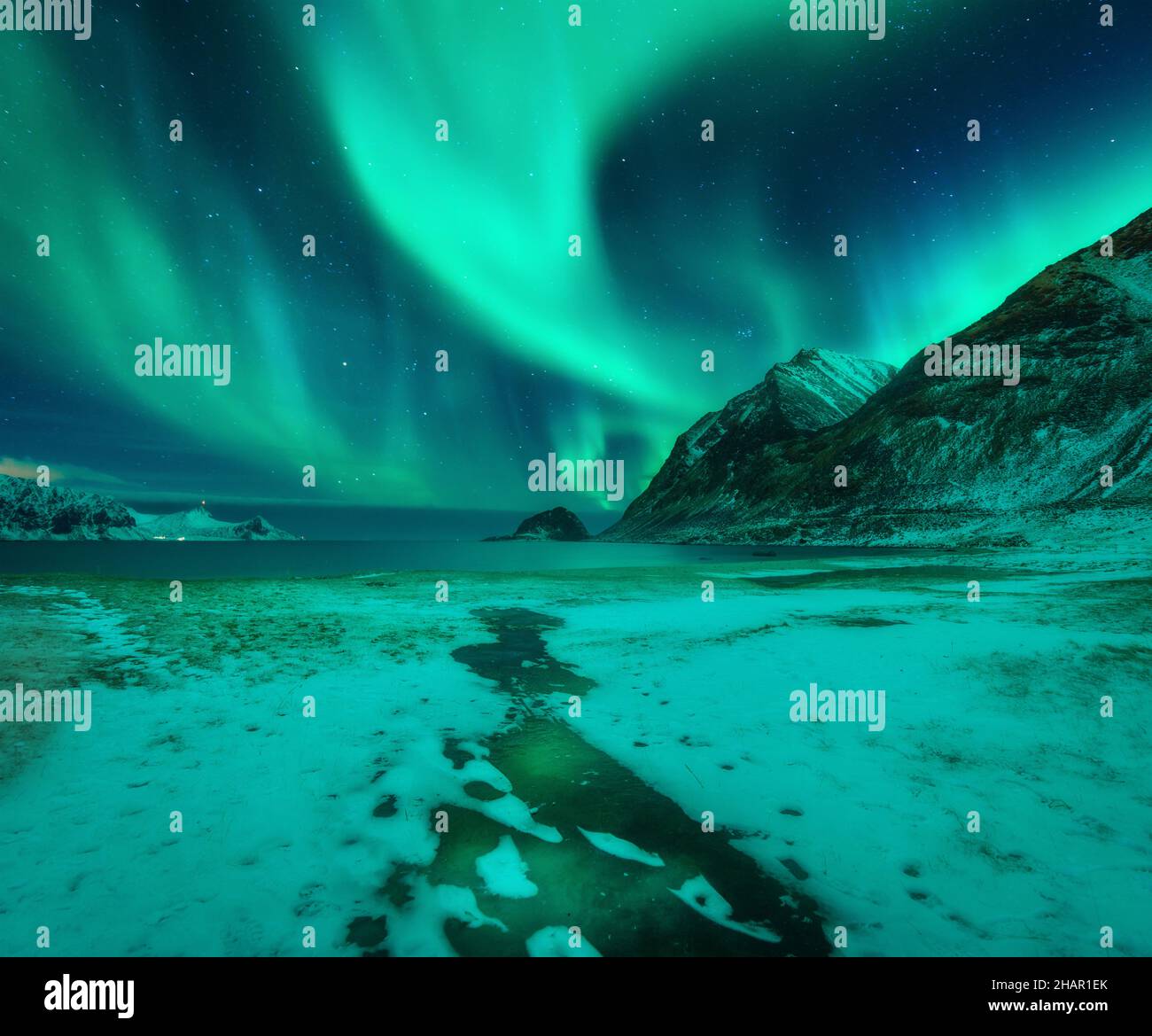 Aurora borealis over snowy mountains and frozen sea coast Stock Photo