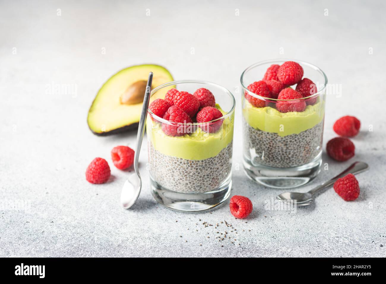 Vegan chia seed pudding with avocado mousse layer and raspberries on a grey concrete background. Healthy food, clean eating dieting and weight loss co Stock Photo