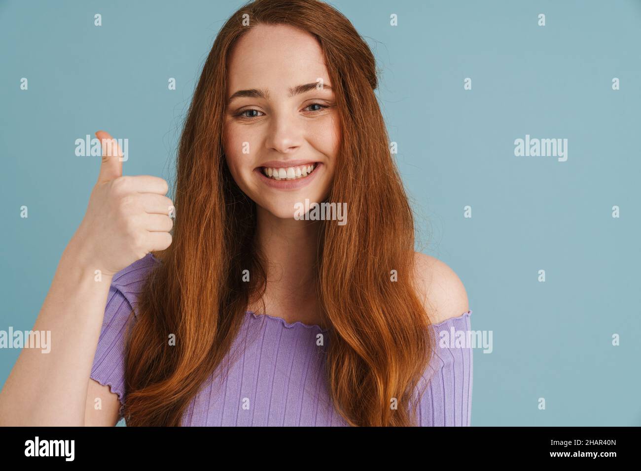 Young ginger woman smiling and showing thumb up at camera isolated over ...
