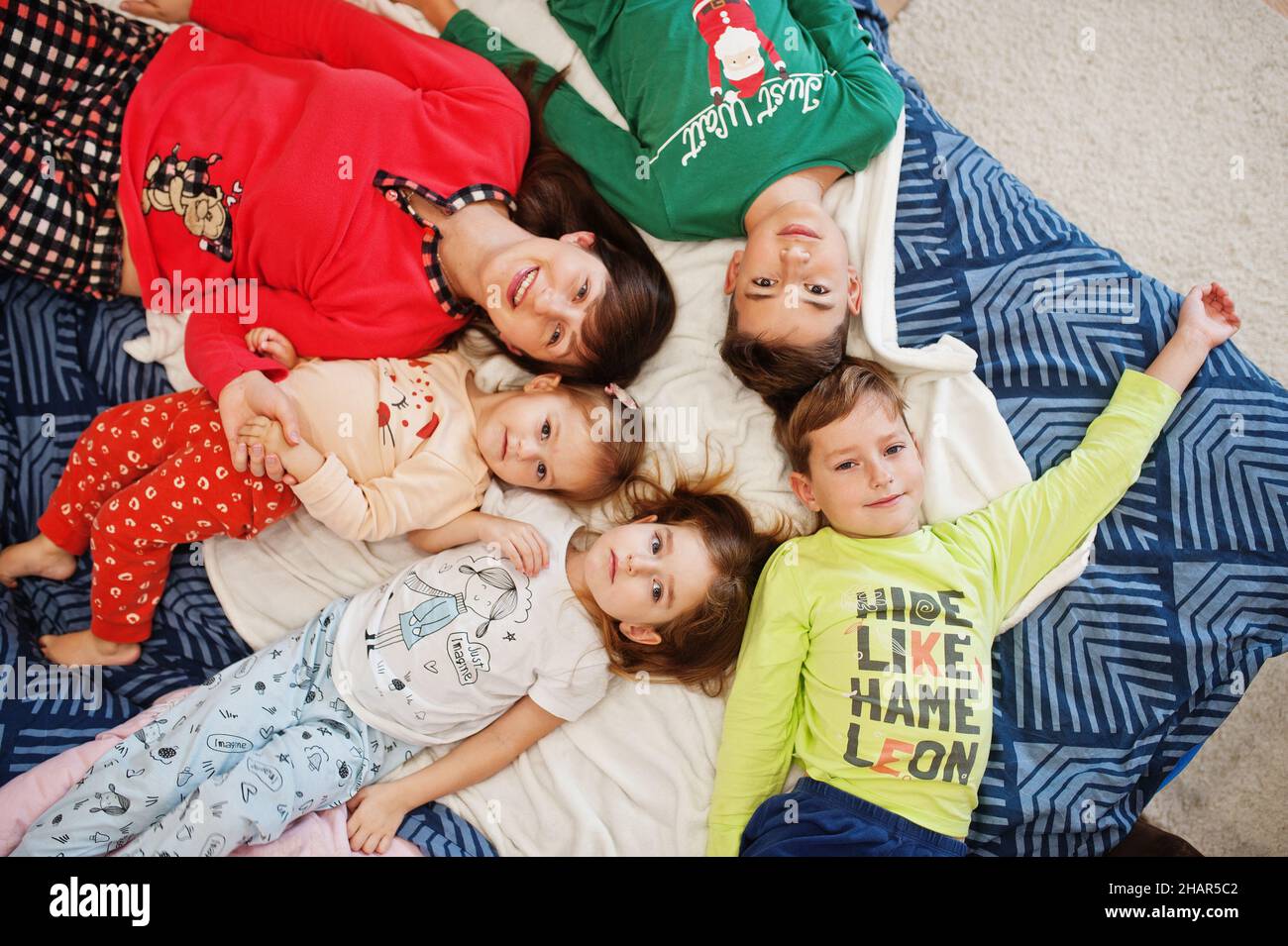 Happy big family is having fun together in bedroom. Large family morning concept. Mother with four kids wear pajamas in bed at home. Stock Photo