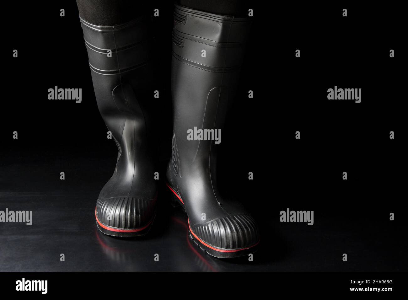 Black Friday for rubber boots. Black rubber boots against a black background. Stock Photo