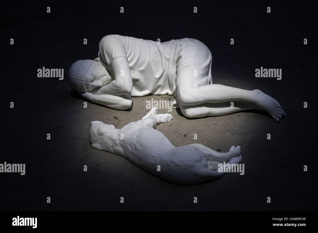 Hangar Bicoccca, Milan: view of Breath Ghosts Blind by Maurizio Cattelan, Carrara white marble sculpture of a person and a dog lying facing each other Stock Photo