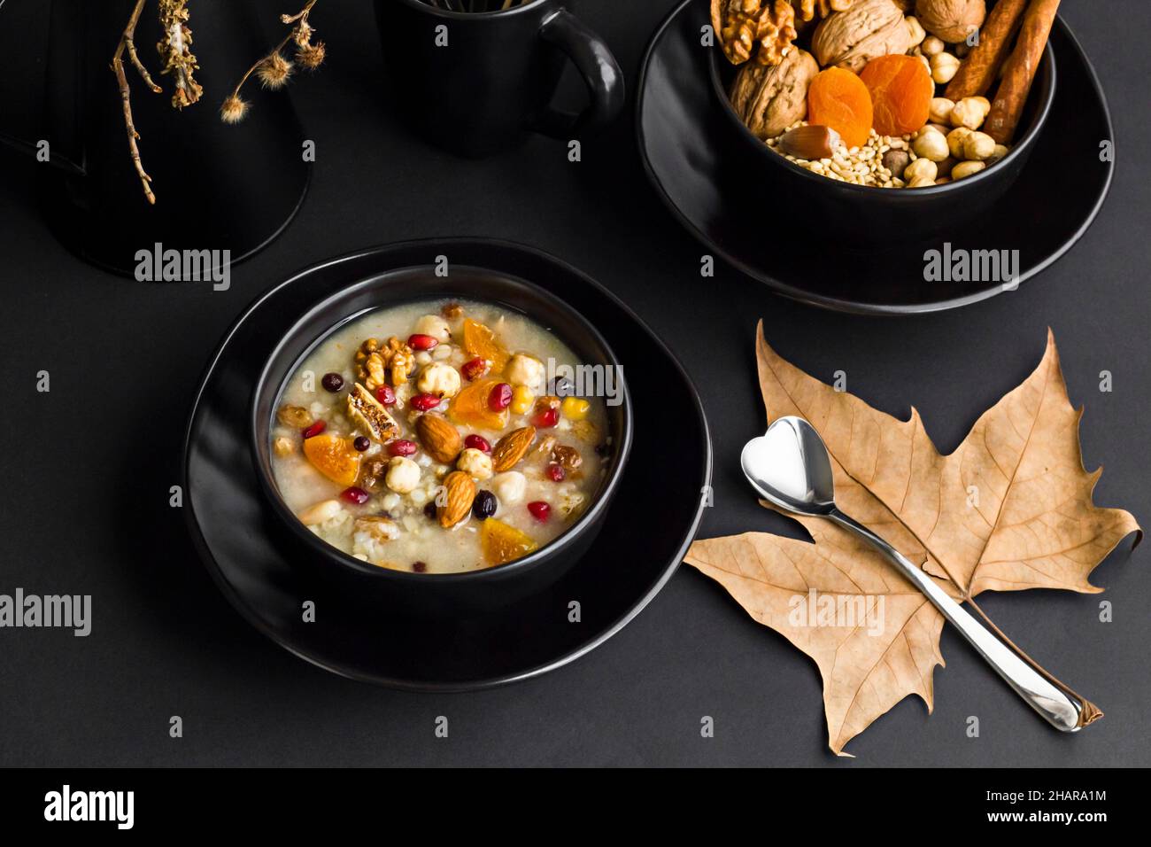 Traditional Turkish Dessert is Asure or Noah's Pudding in stylish,black color bowl on the black surface.Conceptual design. Stock Photo