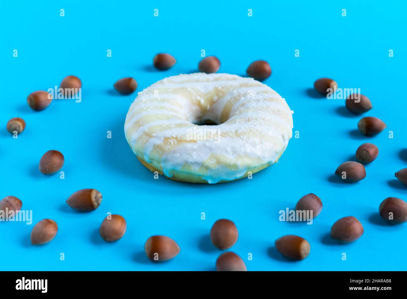 Donut with hazelnuts on a blue background, close up Stock Photo