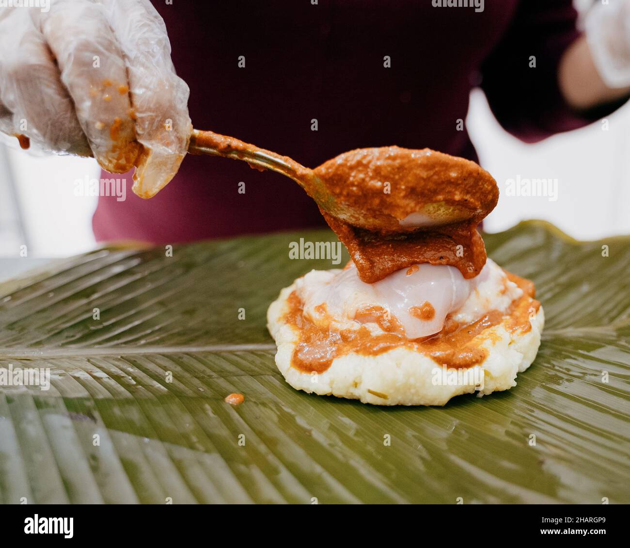 Unrecognizable woman preparing a Guatemalan Tamal adding sauce called Recado before wrapping and cooking it Stock Photo