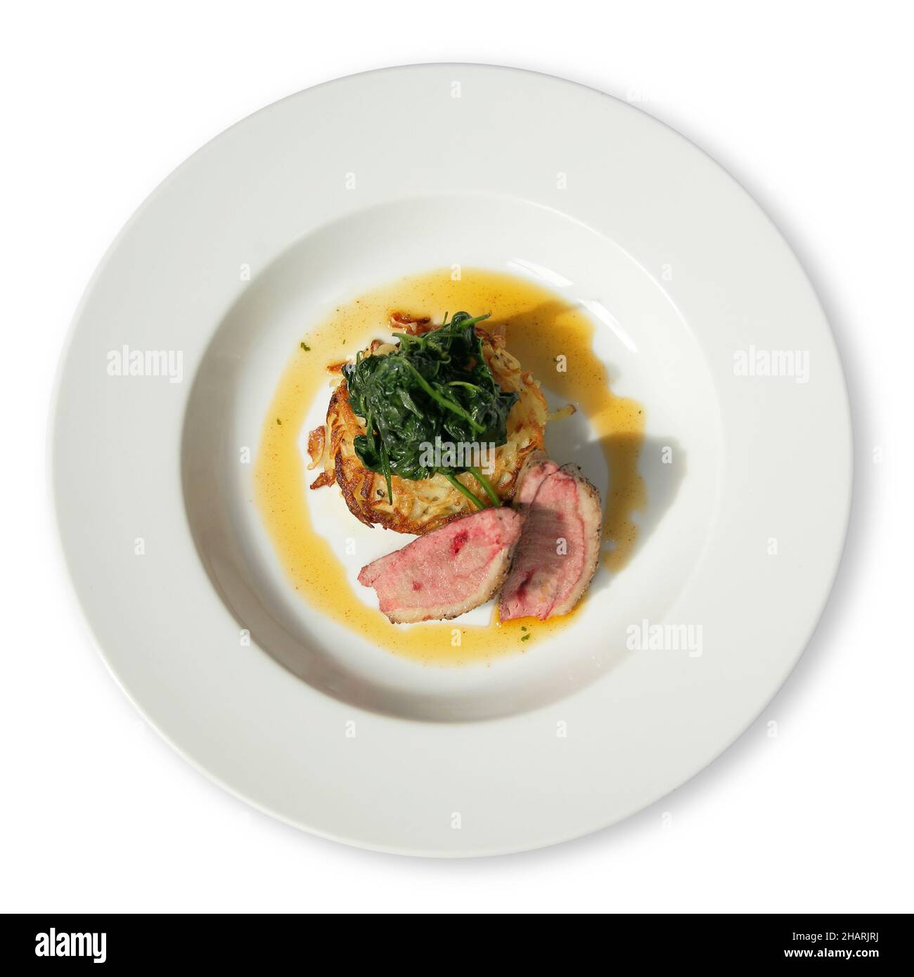 White diner plate with lamb loin spinach and potato rosti Stock Photo