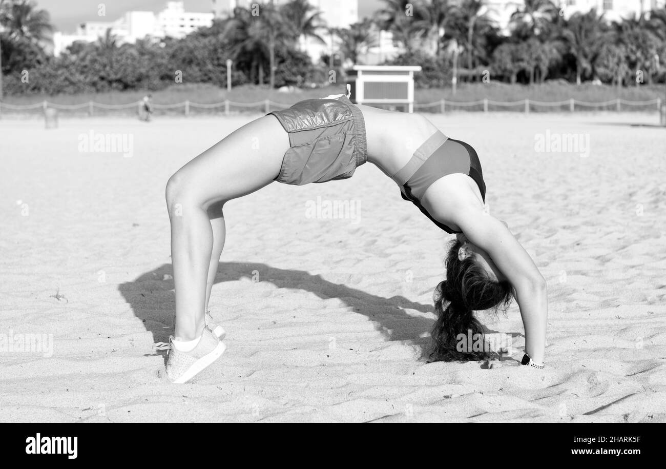 flexible girl in sportswear stand in bridge pose on beach. fit your body. summer activity and fun Stock Photo