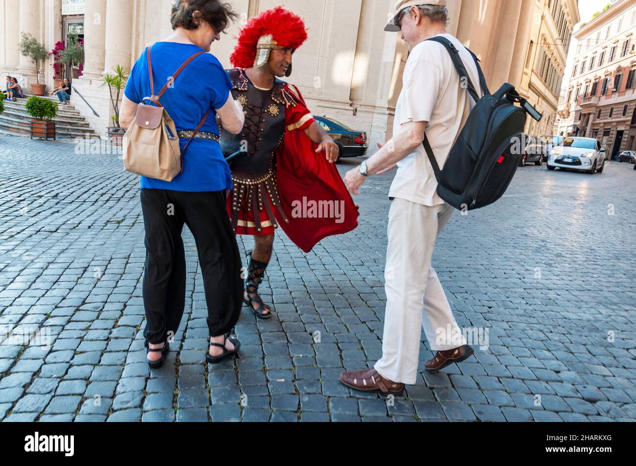 ROME, ITALYA - JUNE 2, 2014: Gladiator impersonator near Colosseum entertains tourists to take photos with them Stock Photo