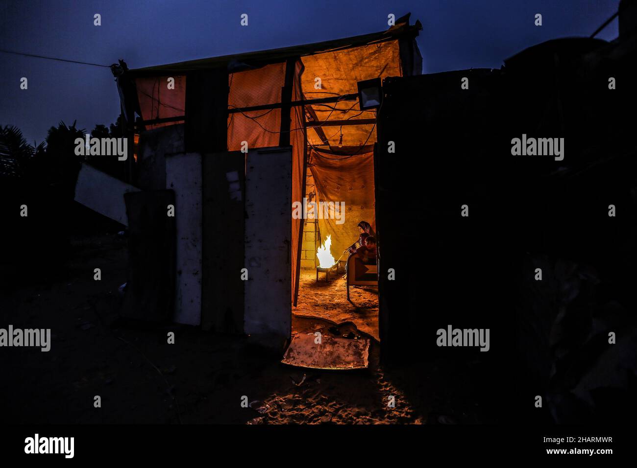 A Palestinian family sits around a fire to keep themselves warm inside ...