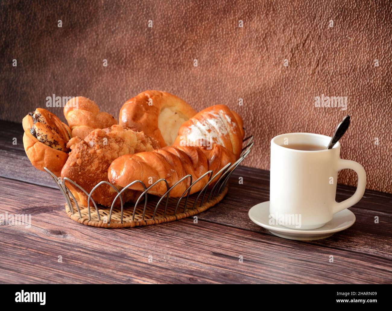 An assortment of homemade cakes on a decorative tray and a cup of hot black tea on a wooden table. Close-up. Stock Photo