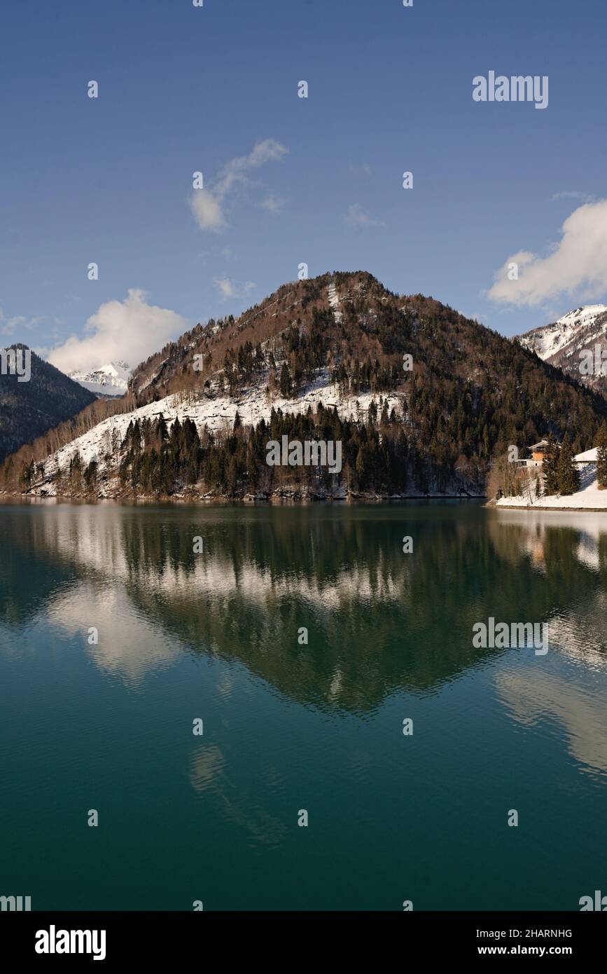 Vertical shot of a lake reflecting the hill with a coniferous forest ...