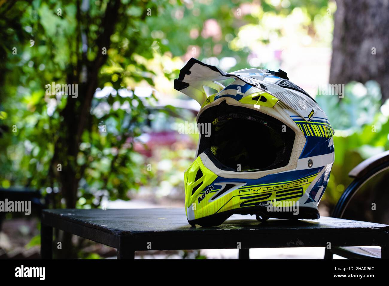 PHNOM PENH, CAMBODIA - Nov 02, 2021: A yellow and blue Airoh aviator 2.3 motocross helmet on a table outdoors on a sunny day Stock Photo