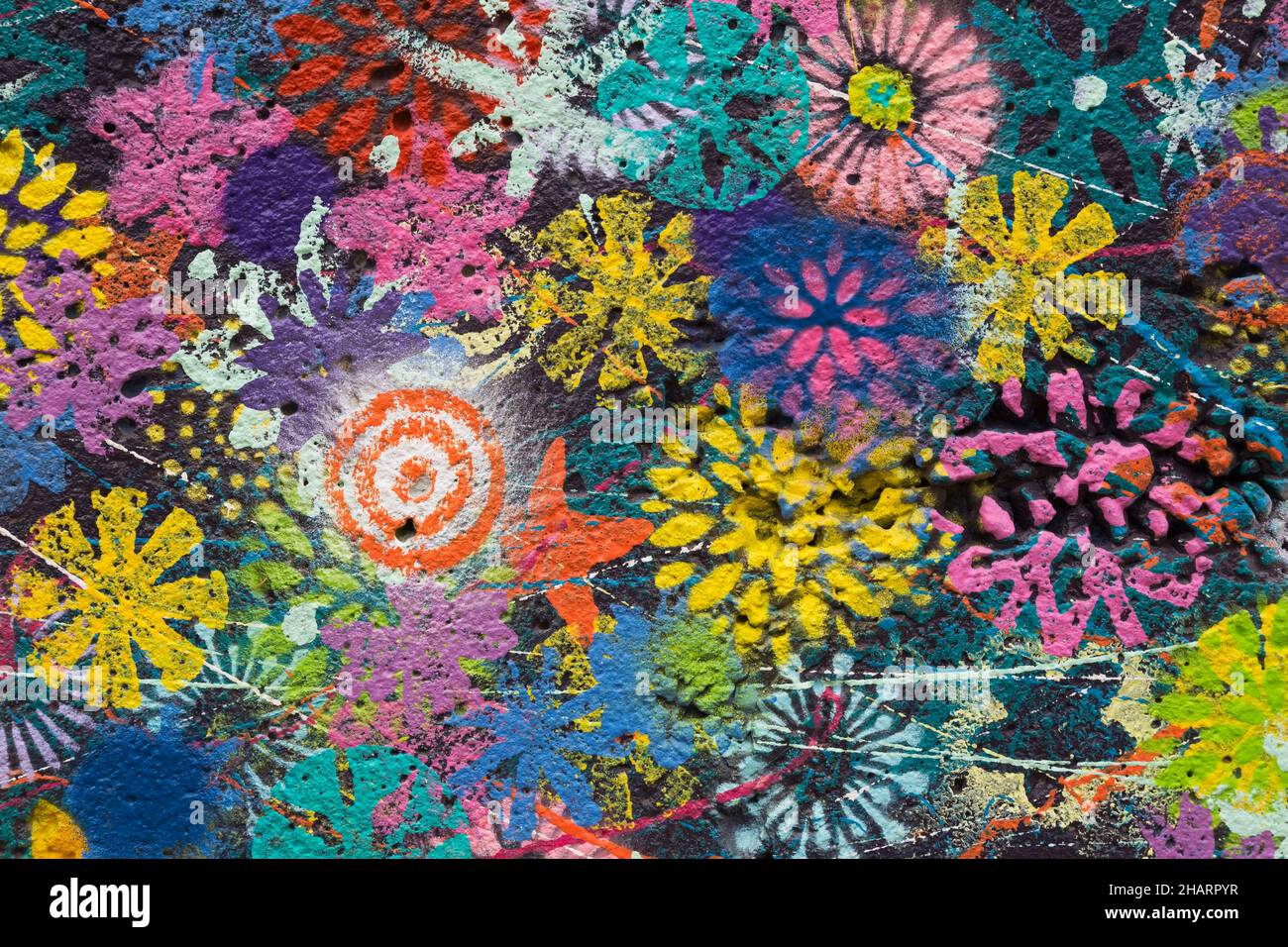 Colourful painted flower patterns on dark blue concrete wall. Stock Photo
