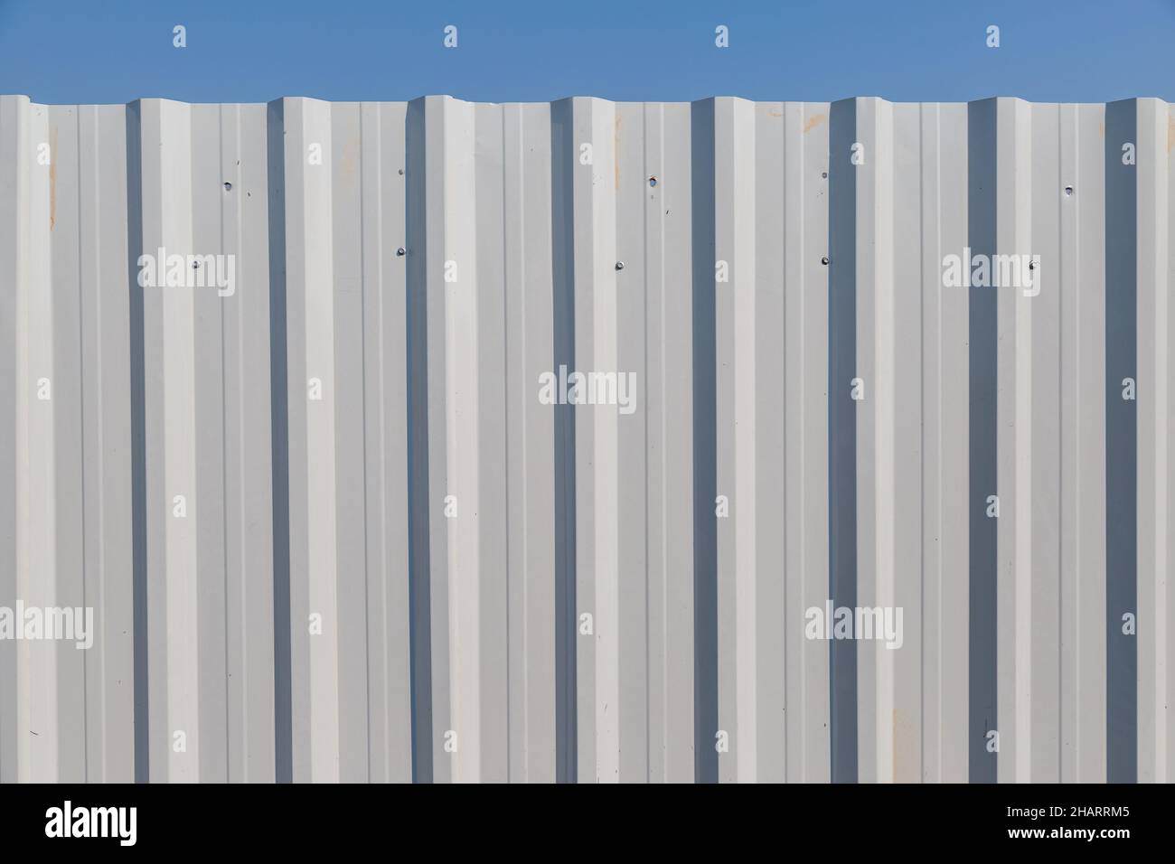 White corrugated metal fence with blue sky background Stock Photo - Alamy