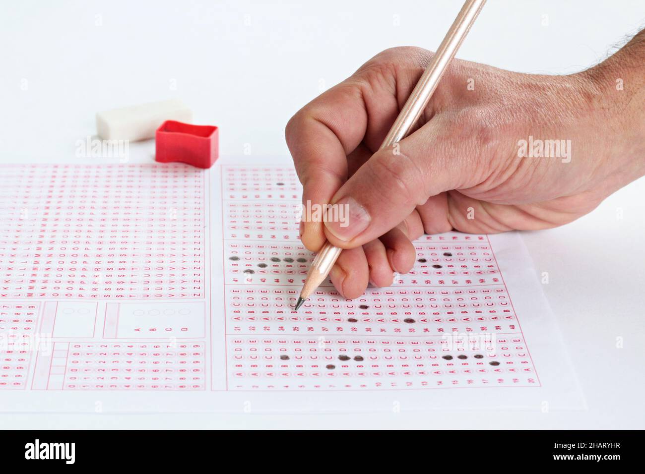 Hand is filling sheet of exam with wooden pencil,conceptual image of education qualifying test exam. Stock Photo