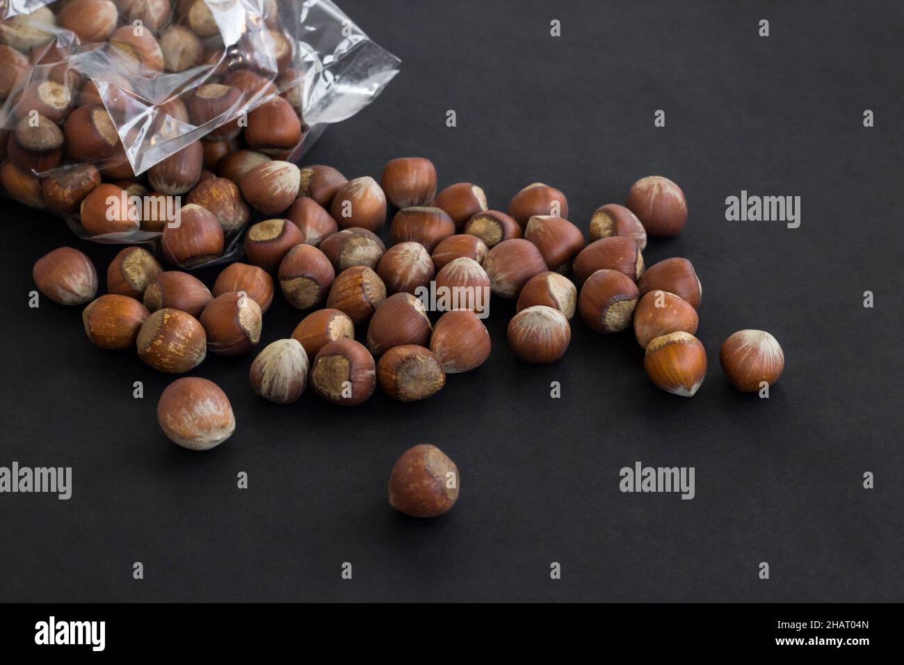 Ripe,delicious hazelnuts fall out of own package on black surface.Above ...