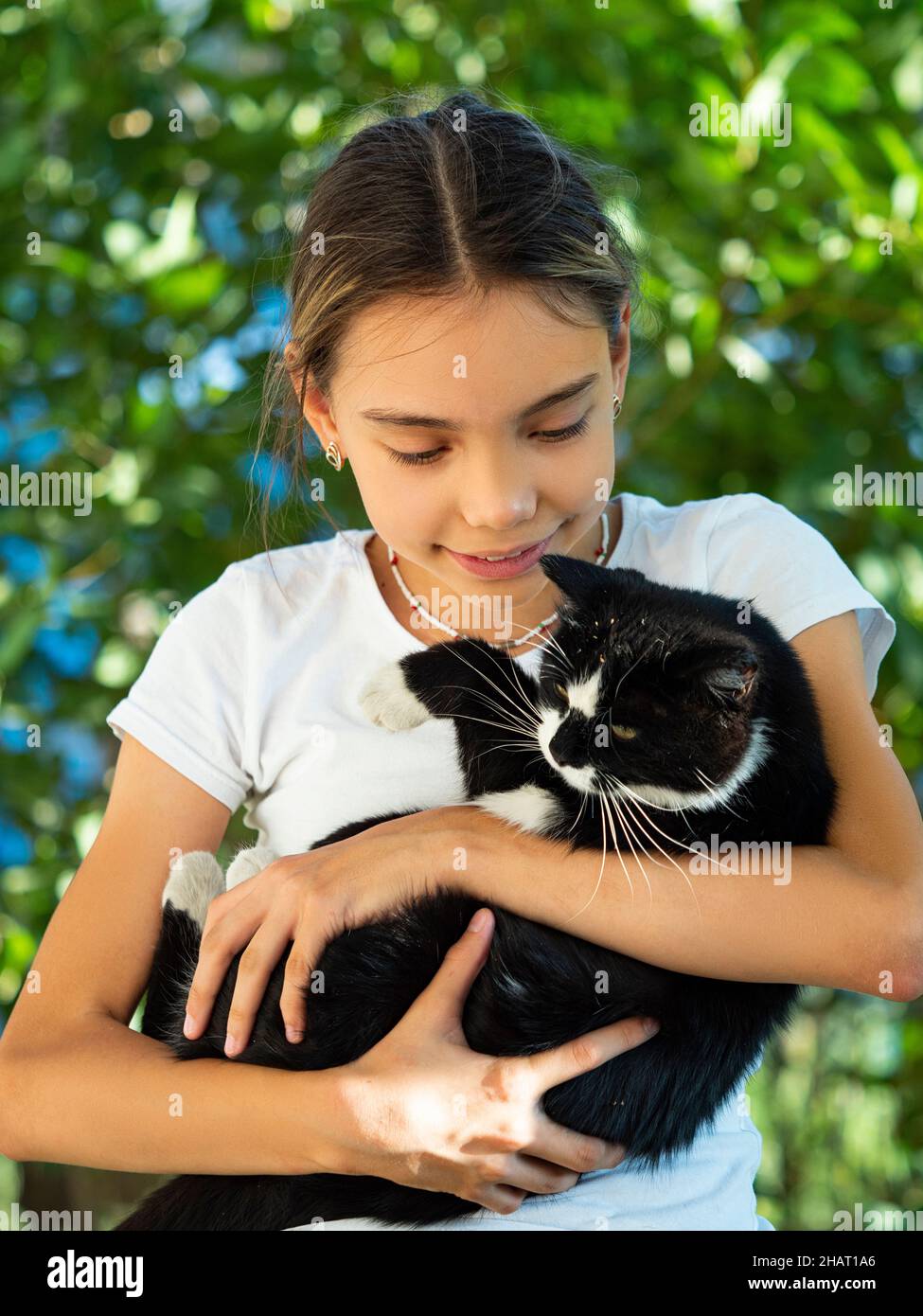 The girl holds a black stray cat in her arms and looks at him. Animal care concept. Stock Photo