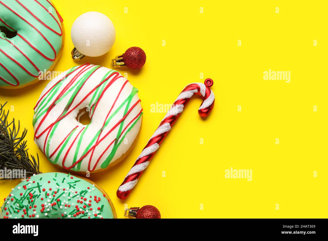 Tasty Christmas donuts with fir tree branch, balls and candy cane on