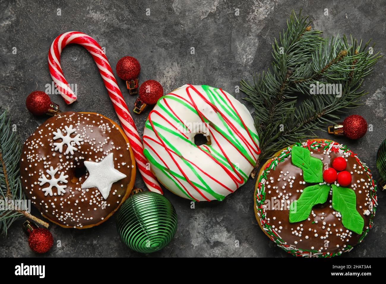 Tasty Christmas donuts with fir tree branches, balls and candy cane on