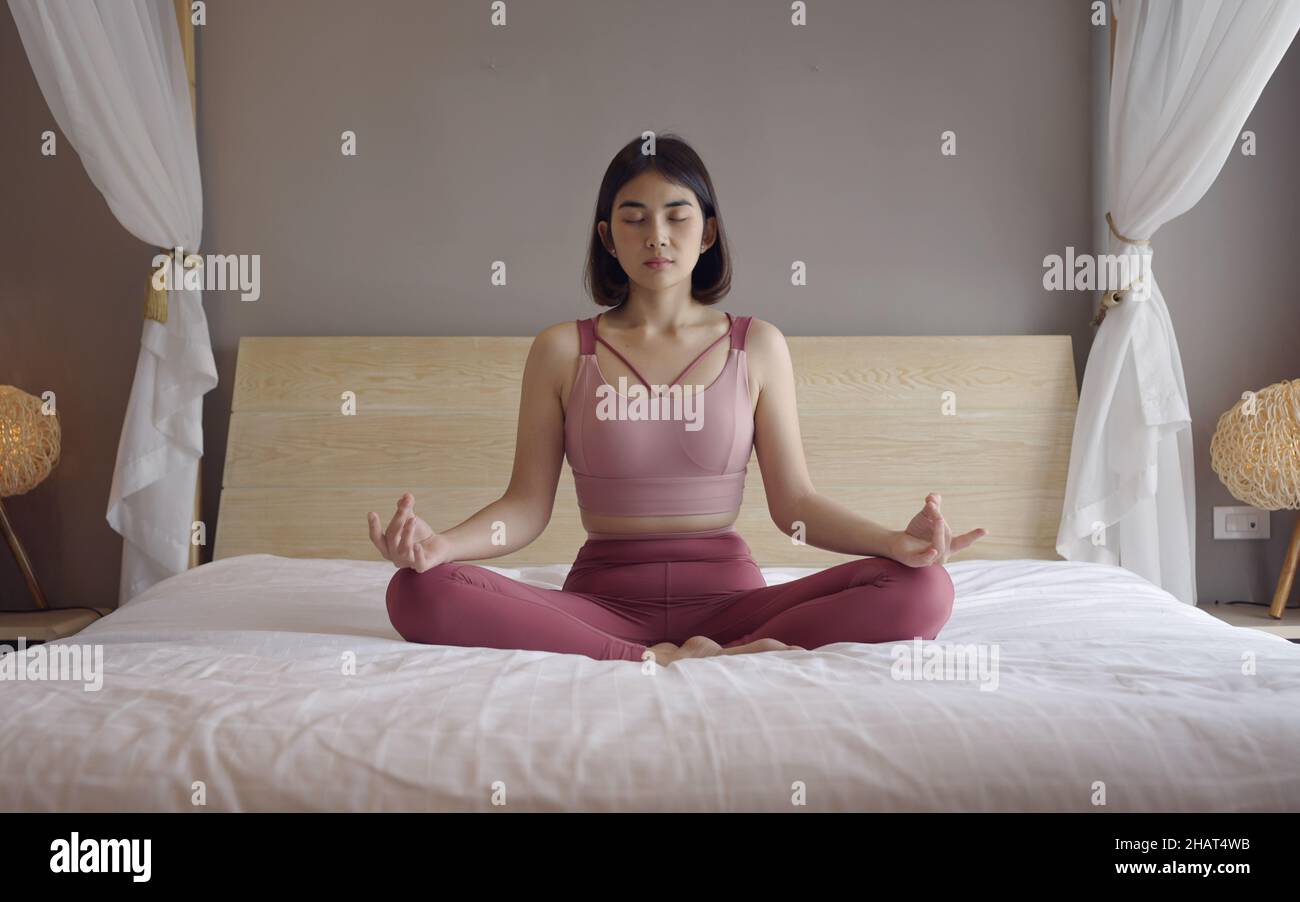 Woman in sportsware practice yoga lotus pose to meditation at home, Wellness woman doing yoga for breathing and meditation comfortable and relax. Stock Photo