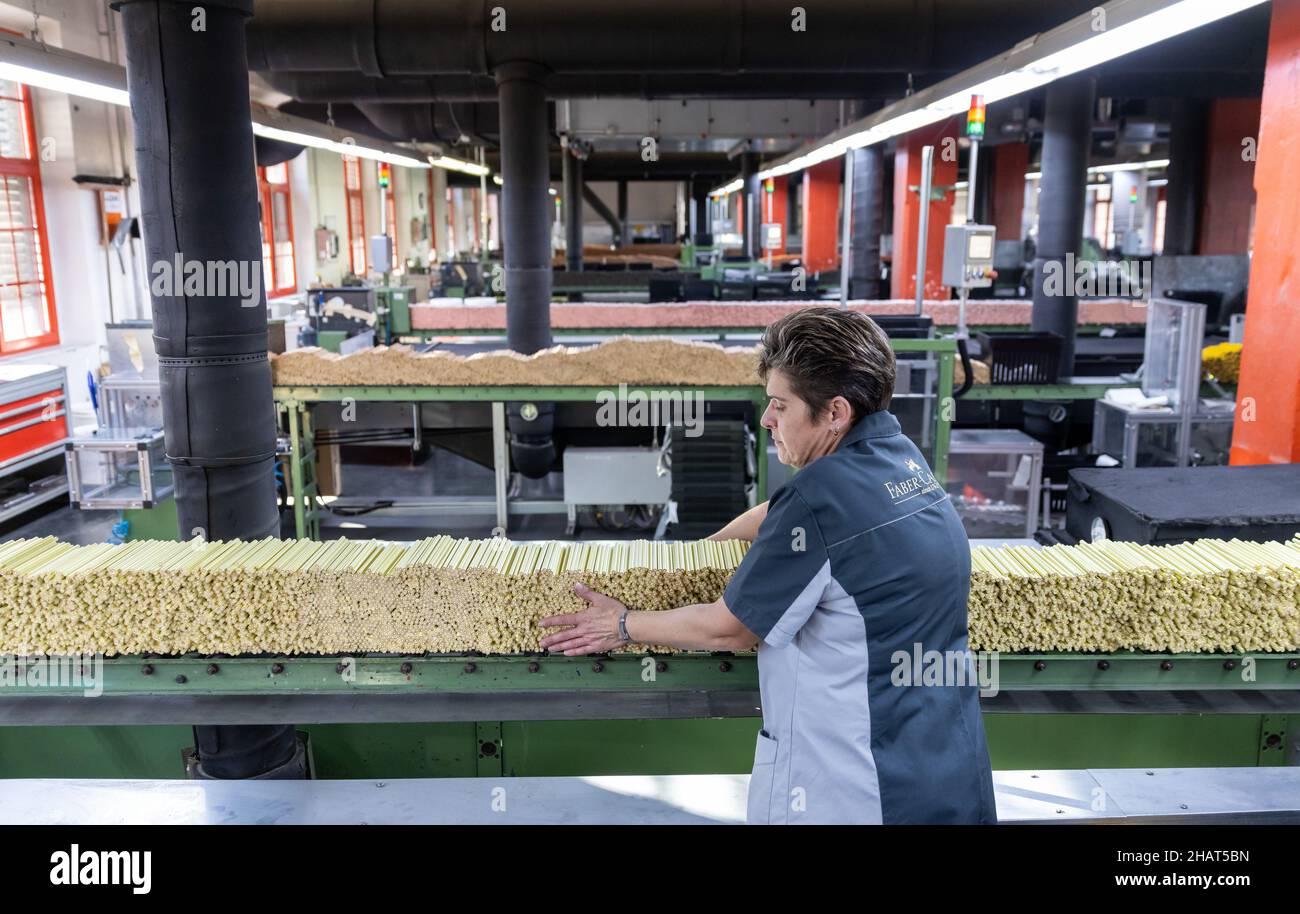 Stein, Germany. 24th Nov, 2021. An employee of stationery manufacturer Faber-Castell places pencils on a conveyor belt in the company's crayon paint shop. Credit: Daniel Karmann/dpa/Alamy Live News Stock Photo