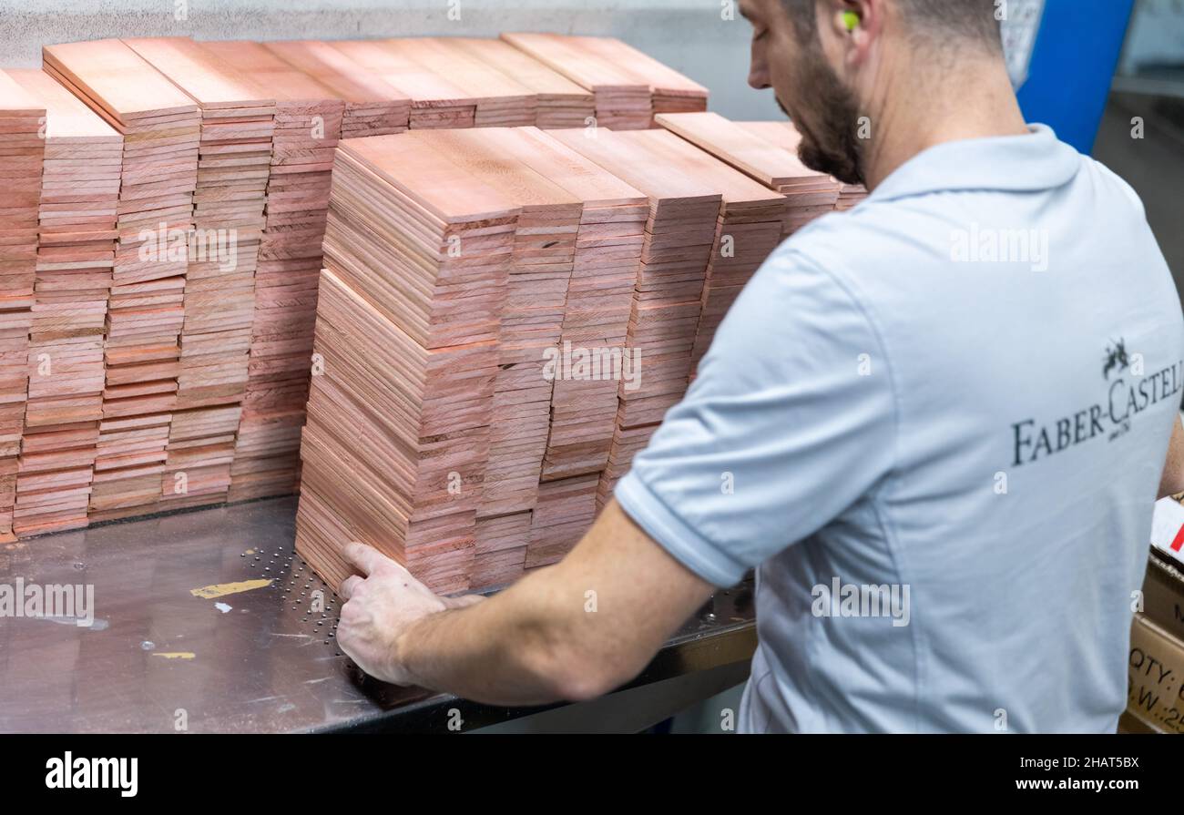 Stein, Germany. 24th Nov, 2021. An employee of the stationery manufacturer Faber-Castell places wooden boards in the company's production line. Credit: Daniel Karmann/dpa/Alamy Live News Stock Photo