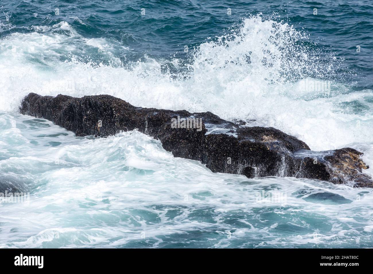 Splashing Water on a small rock in the Bay of Hermanus in the Western Cape of South Africa Stock Photo