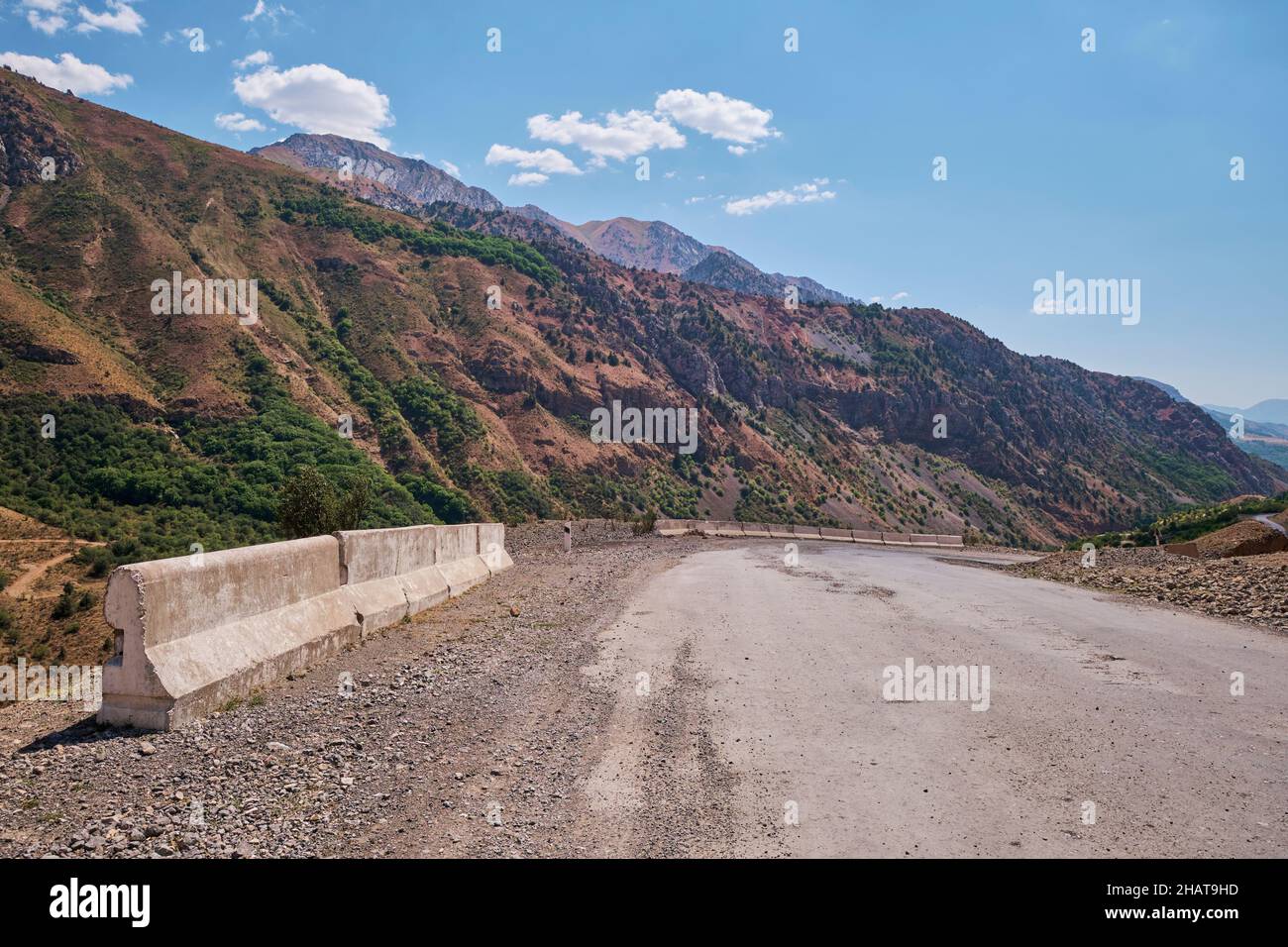 White concrete barriers at a dangerous curve in the road. In the Lake Charvak resevoir area near Tashkent, Uzbekistan. Stock Photo