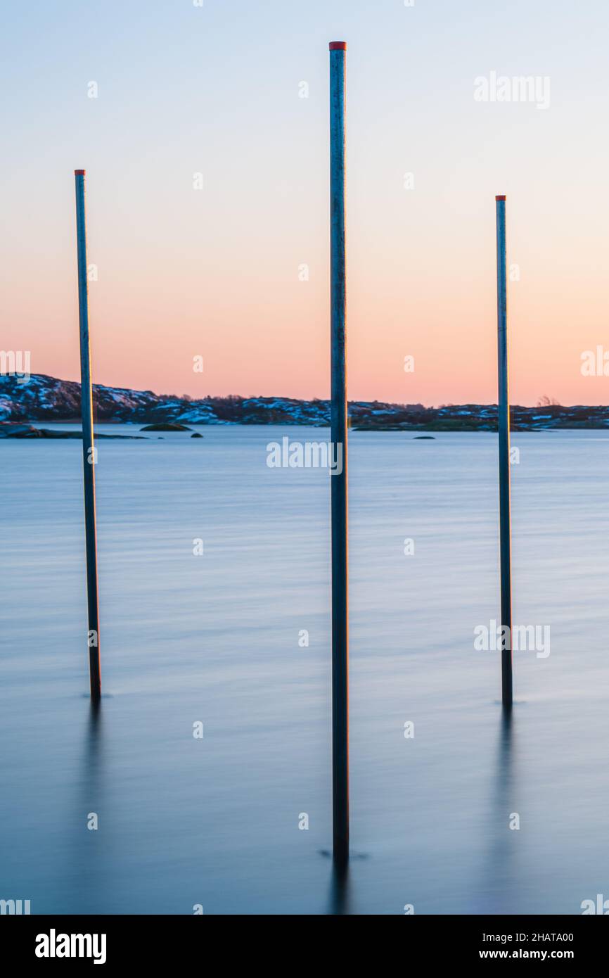 Poles standing in sea at sunset Stock Photo