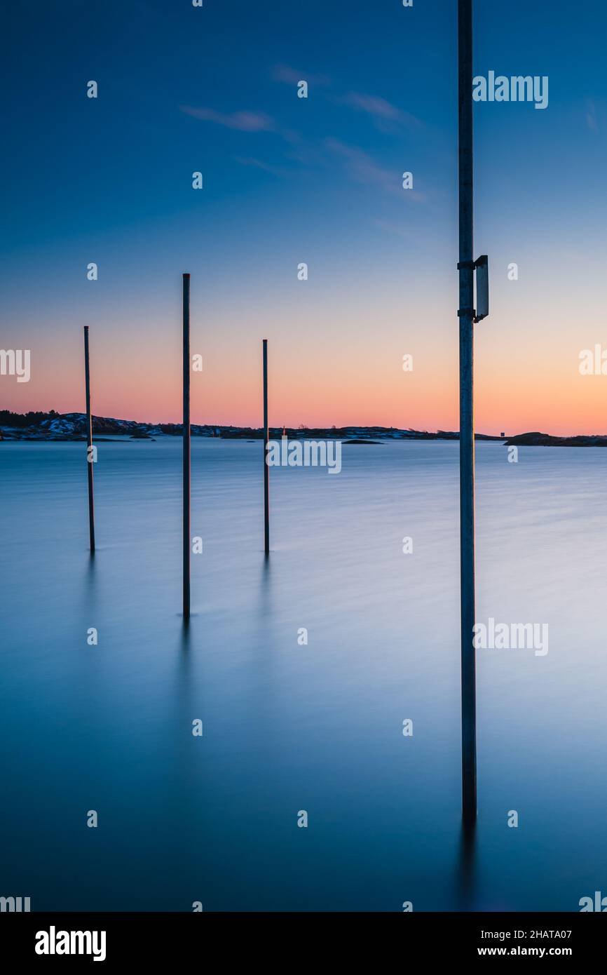 Poles standing in sea at sunset Stock Photo