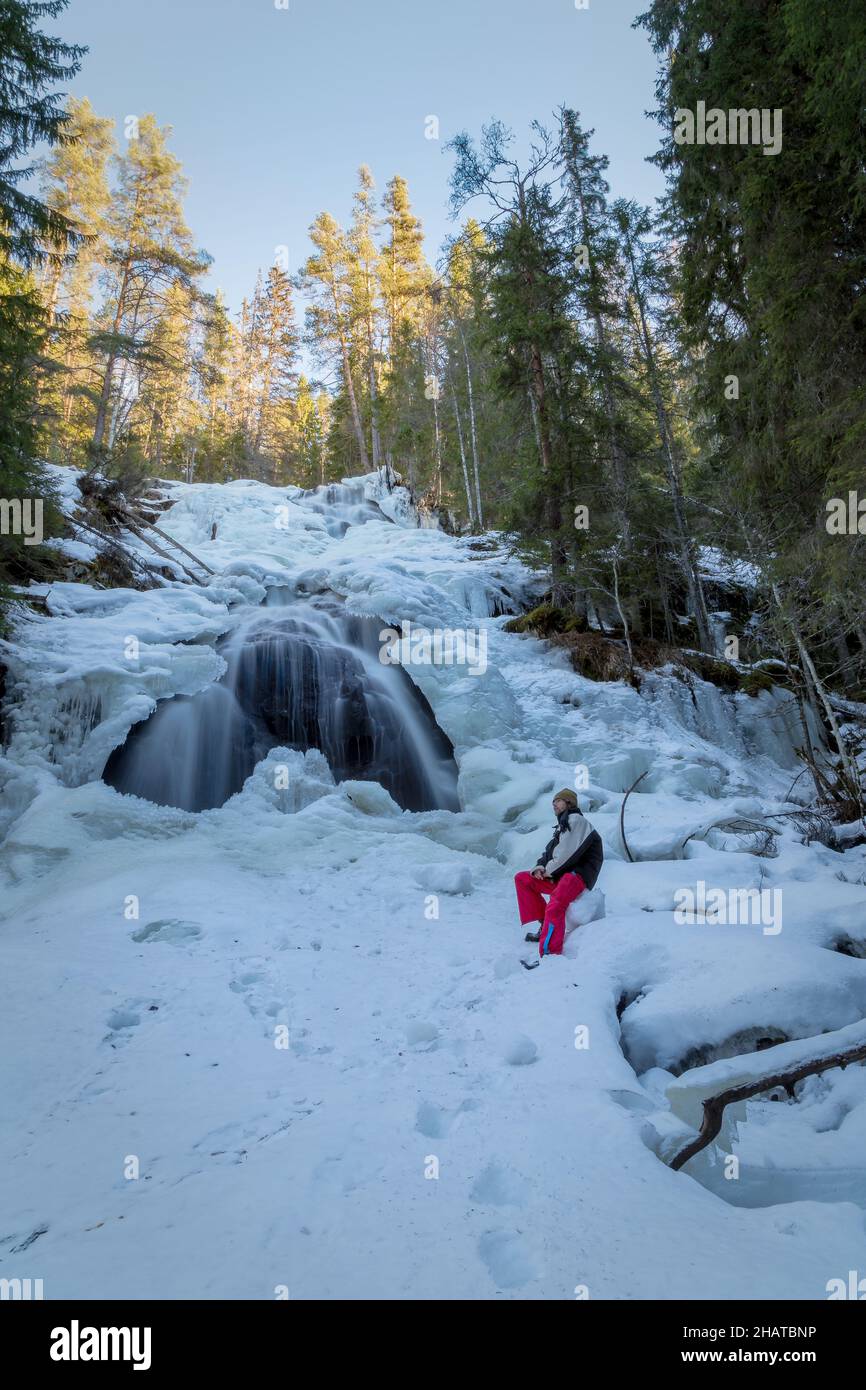 man and a waterfall with ice and snow in a forest Stock Photo