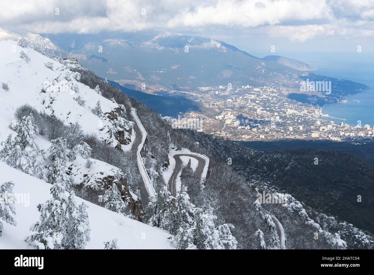 Winter Yalta view Ai-Petri. Mountain serpentine in the snow. Fluffy snow trees. Panorama view of the city from above. A winding snow-covered road. Maj Stock Photo