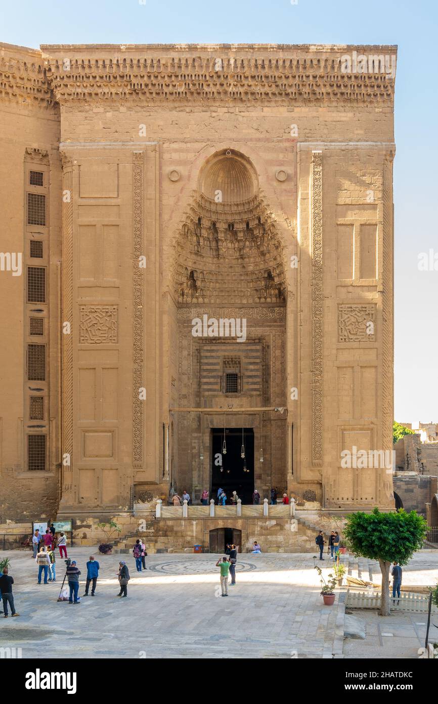 Cairo, Egypt - November 27 2021: Facade of Islamic Mamluk era Mosque and Madrassa of Sultan Hassan, with few visitors, Old Cairo Stock Photo