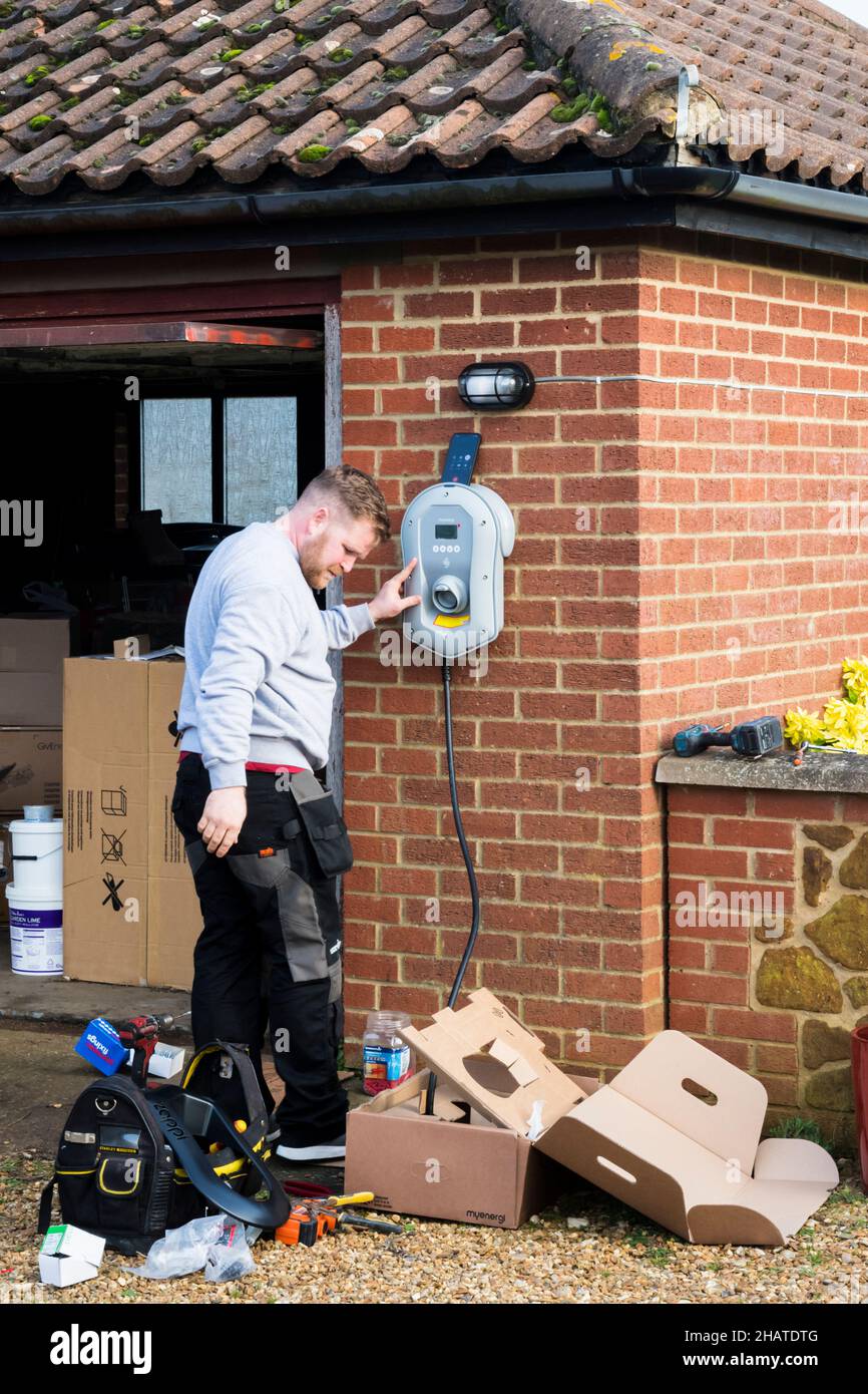 Electrician fitting a Zappi electric car charger to the outside wall of