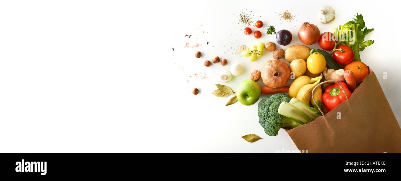 Background with recyclable brown paper shopping bag with fruits and vegetables on white table. Top view. Horizontal composition. Stock Photo