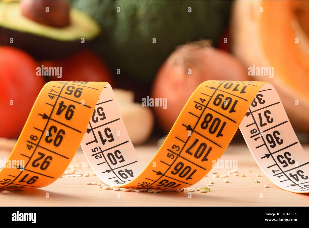 Weight control concept with macro view of tape measure and healthy food background. Front view. Horizontal composition. Stock Photo