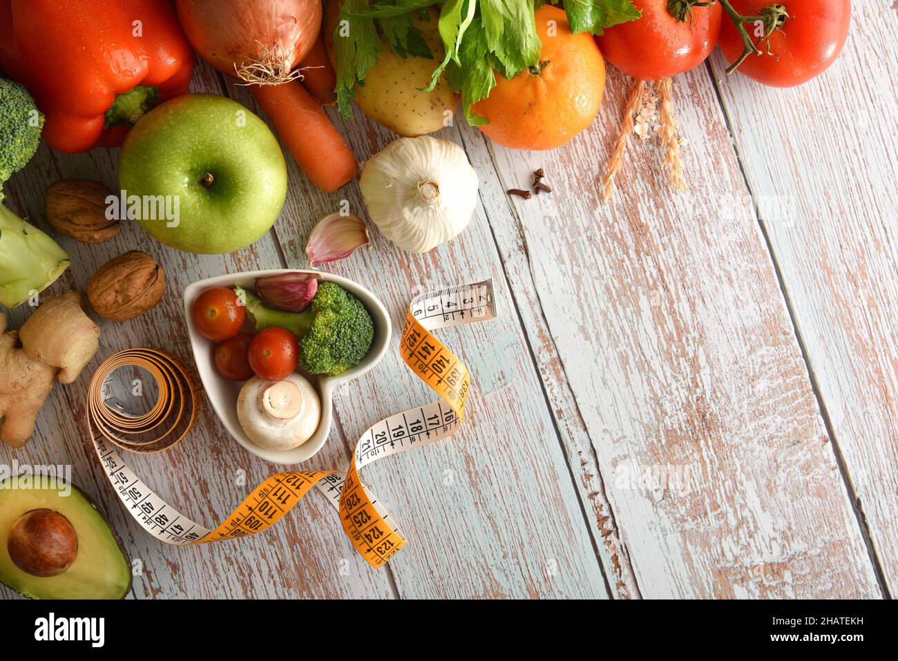 Balanced menu concept with fruits and vegetables on wooden table and heart-shaped bowl and measuring tape. Top view. Horizontal composition. Stock Photo