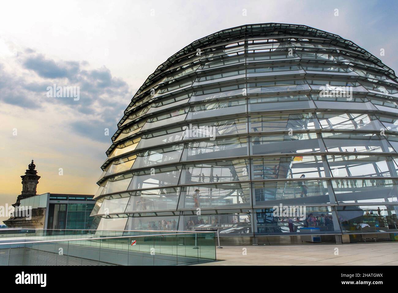 Reichstag dome exterior in summer. Yellow sunlight reflection on glass window. Popular tourist attraction. Cloud in blue sky. Stock Photo