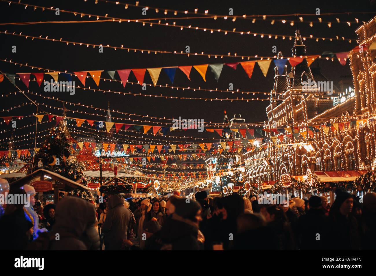 A crowd of people walking in the evening at the famous Christmas fair in the center of Moscow decorated with festive golden garlands. Magic atmosphere Stock Photo