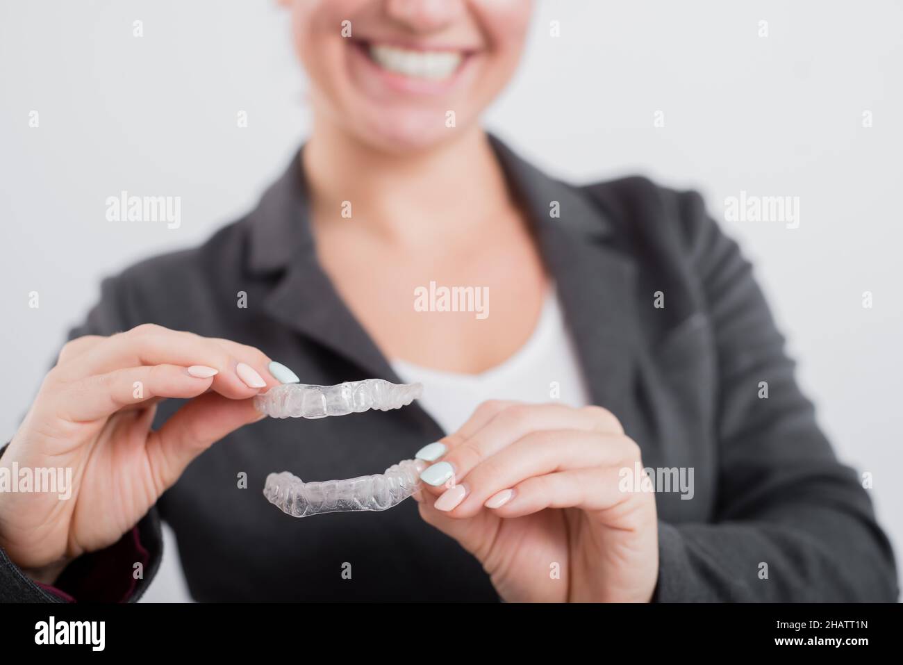 A woman is holding a transparent plastic mouth guard. Orthodontist's